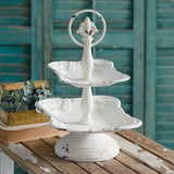Three-tiered white decorative tray on a wooden surface with a rustic background