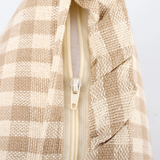 Close-up of a textured beige fabric with a zipper on a light gray background