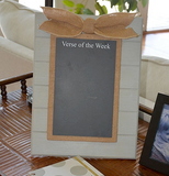 Decorative frame with a chalkboard and burlap bow on a wooden surface.
