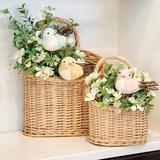 These baskets offer a charming accent for decorative displays. Made from woven willow with a natural light wood hue, the baskets feature a classic oval shape and single arched handle. They are perfect for displaying floral arrangements, decorative stakes, or other items.

Materials:
Willow

Dimensions:
Smaller basket -
8 1/4" wide x 4" deep x 10 1/2" high

Larger basket -
11 1/2" wide x 5 1/2" deep x 15 1/4" high