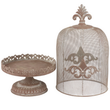 Decorative metal cake stand and dome with intricate designs on a white background