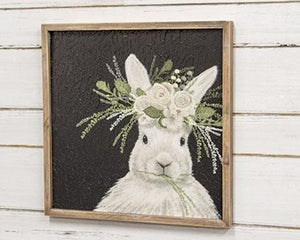 White bunny rabbit with white and green floral crown in front of a black textured background inside brown wooden frame