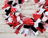 Hand-tied red and black buffalo plaid fabric rag garland banner displayed horizontally against a rustic backdrop.